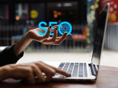 A person interacting with a laptop, with a glowing 'SEO' symbol in hand, symbolizing Eunika Agency’s expertise in search engine optimization and digital marketing strategies.